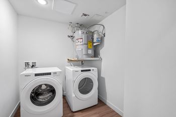 Two white front load washing machines in a laundry room.